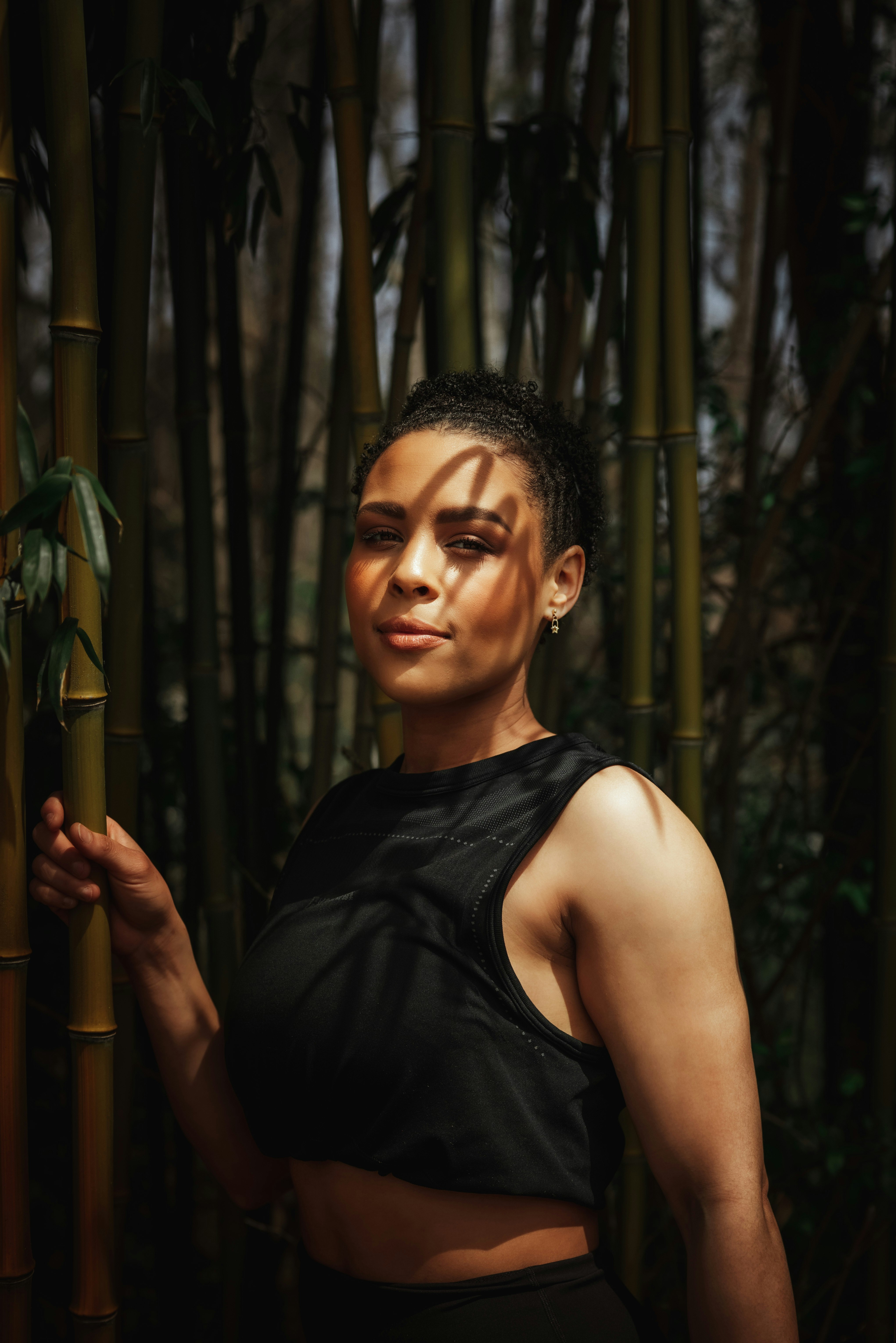 woman in black tank top standing beside green leaf tree during daytime